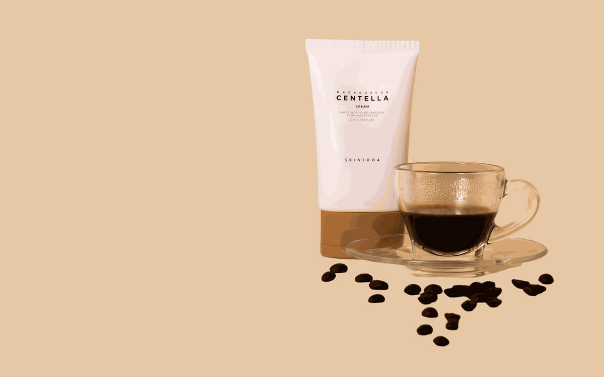 Madagascar centella cream SKIN1004 in tubo rosa chiaro e marrone, accanto a una tazza di caffè in vetro